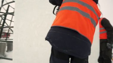 Turuncu yansıtıcı yelek ve kask takan işçiler elektrikli testere buz tabakasını özelleştirdiler