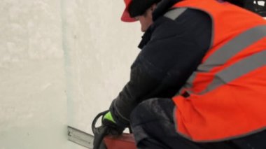 Turuncu yansıtıcı yelek ve kask takan işçiler elektrikli testere buz tabakasını özelleştirdiler