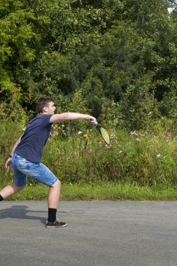 Elinde raket olan genç bir çocuk badminton oynar.