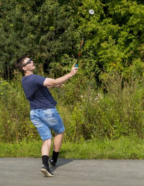 Elinde raket olan genç bir çocuk badminton oynar.
