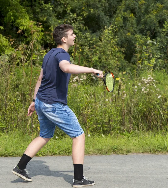 Adolescente chico con una raqueta en la mano juega bádminton — Foto de Stock