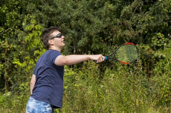 Adolescente chico con una raqueta en la mano juega bádminton — Foto de Stock