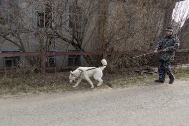Tulumlu bir adam köpekle yürüyüşe çıkıyor.