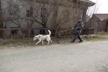 Tulumlu bir adam köpekle yürüyüşe çıkıyor.