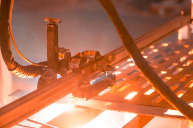 Plazma kesme makinesi, erimiş metal damlalarını farklı yönlere saçarak kalın bir çelik tabakayı yakar.