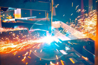 Plazma kesme makinesi, erimiş metal damlalarını farklı yönlere saçarak kalın bir çelik tabakayı yakar.