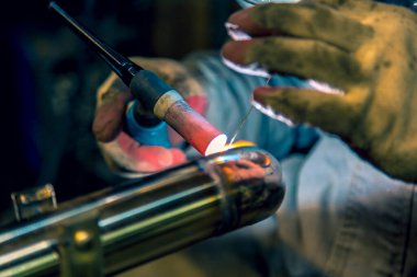 TIG kaynakçısı, parlatılmış paslanmaz çelik boruya dirsek atıyor.