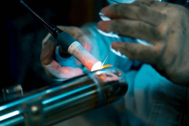 TIG kaynakçısı, parlatılmış paslanmaz çelik boruya dirsek atıyor.