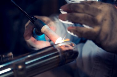 TIG kaynakçısı, parlatılmış paslanmaz çelik boruya dirsek atıyor.