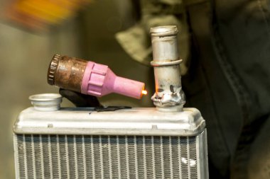 Bir TIG uzmanı küçük bir araba radyatörüne boru kaynak yapıyor.