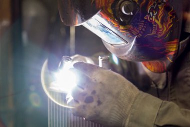 Bir TIG uzmanı küçük bir araba radyatörüne boru kaynak yapıyor.