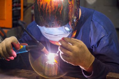 TIG kaynakçısı yolcu vagonunun egzoz sistemi için kaynak yapıyor.