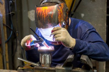 TIG kaynakçısı yolcu vagonunun egzoz sistemi için kaynak yapıyor.