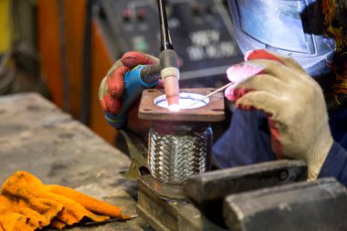 TIG kaynakçısı yolcu vagonunun egzoz sistemi için kaynak yapıyor.