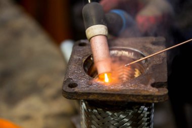 TIG kaynakçısı yolcu vagonunun egzoz sistemi için kaynak yapıyor.