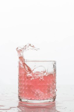 Beyaz arka planda sıçramaları olan bir bardak taze içki. Dondurulmuş hareket. Trendy renk 2019, mercan