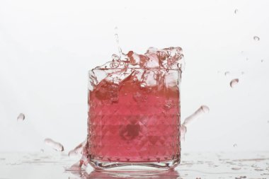 Beyaz arka planda sıçramaları olan bir bardak taze içki. Dondurulmuş hareket. Trendy renk 2019, mercan