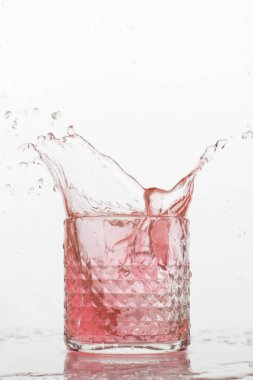 Beyaz arka planda sıçramaları olan bir bardak taze içki. Dondurulmuş hareket. Trendy renk 2019, mercan