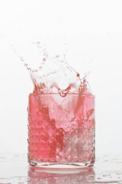 Beyaz arka planda sıçramaları olan bir bardak taze içki. Dondurulmuş hareket. Trendy renk 2019, mercan