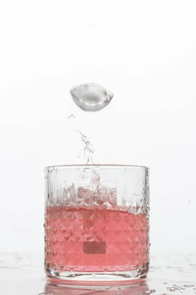 Beyaz arka planda sıçramaları olan bir bardak taze içki. Dondurulmuş hareket. Trendy renk 2019, mercan