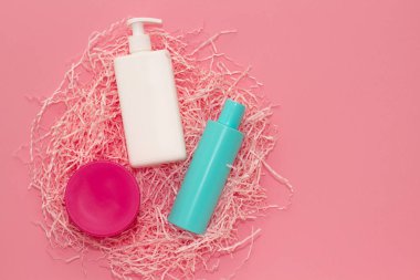 Spa kozmetik jakuzileri ve şişeler, markalaşma modeli, pembe arka planda üst manzara.