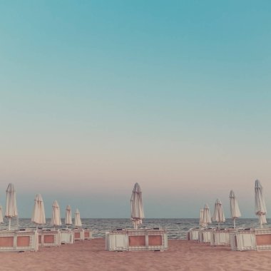 Plaj kapalı şemsiye ve şezlong akşam ile. Tonda.