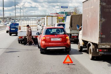 MOSCOW, RUSSIAN FEDERATION - AUGUST 04, 2017 : Accident-red car crashed into the truck in the middle of a four-lane highway (MKAD). Put up an emergency stop sign, a frustrated truck driver walking around the car. clipart