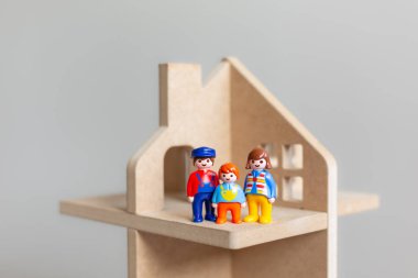 Üç erkek bir adam, bir kadın ve bir çocuk bir ahşap oyuncak evde rakamlar oyuncak. Yeni evlerine bir ailede bir sembolü. Yakın çekim.