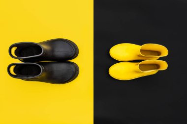 Gumboots - sarı kadın ve siyah erkek - birbirlerine ters ters arka planlar üzerinde duran iki çift. Üstten görünüm. Sonbahar renkli ve canlı kavramı
