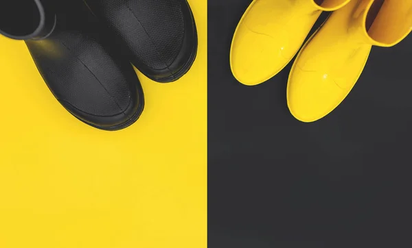 Black and yellow rubber boots on yellow and black backgrounds. The view from the top. Bright and contrast the concept of autumn. Copy space.