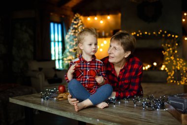 Kim bir masaya oturur ve tatlılar bir Noel hediyesi yiyor küçük torunu ile genç bir büyükanne. Noel aile sabah kavramı.