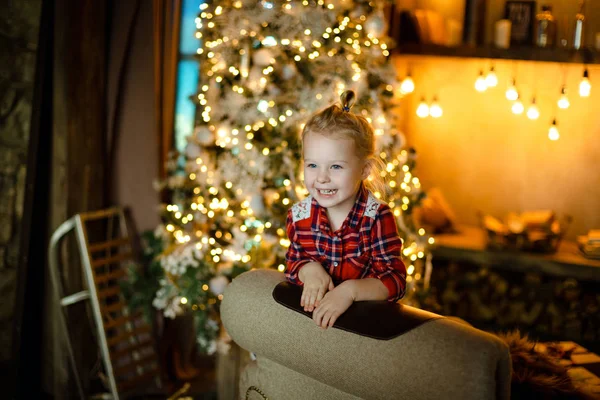 一个迷人的白人女孩在装饰圣诞树和燃烧的花环的背景上玩耍和大笑 家庭舒适的圣诞节概念 — 图库照片