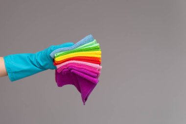 Bir elinde bir lastik eldiven tarafsız bir arka plan üzerinde renkli mikrofiber bezler bir dizi tutar. Parlak bahar, bahar temizliği kavramı.
