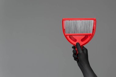 Bir lastik eldiven elinde bir kepçe ile bir salkım tarafsız bir arka plan üzerinde tutar. Parlak bahar, bahar temizliği kavramı.