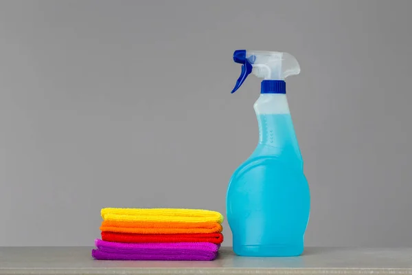 A set of colorful cleaning clothes and a cleaning agent in blue spray bottle. Place for text. Concept  spring cleaning.