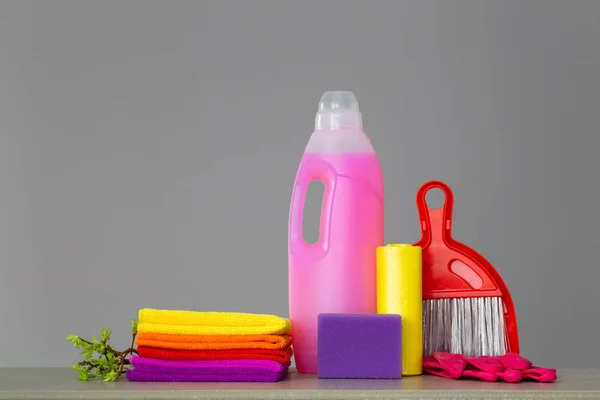 Colorful set of tools for cleaning the house and twigs with green leaves on neutral background. The concept of spring cleaning. Copy space.