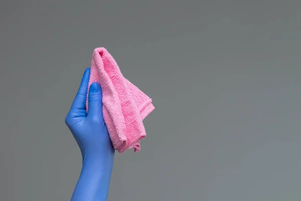 Elinde lastik eldiven parlak mikrofiber duster tarafsız bir arka plan üzerinde tutar. Bahar Temizlik kavramı.