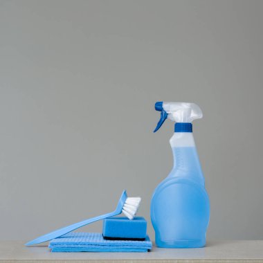 Mavi püskürtülen ilaç şişe Plastik Sabunluk ile temizlik, sünger, yemek için fırça ve bez toz için gri arka plan üzerinde ovma. Temizlik araçları. Kopya alanı.