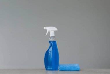 Mavi püskürtülen ilaç şişe Plastik Sabunluk ve gri arka plan üzerinde toz için bez ile temizlik. Temizlik araçları. Kopya alanı.