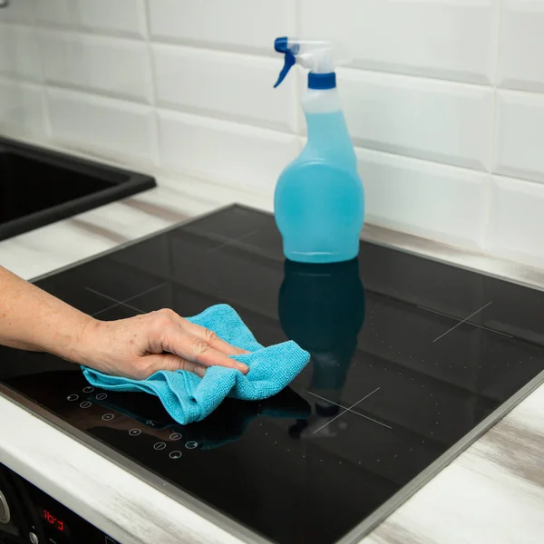 Kvinnas Hand Med Blå Mikrofiberduk Gnuggar Keramisk Glasplatta Köket Bakgrunden — Stockfoto