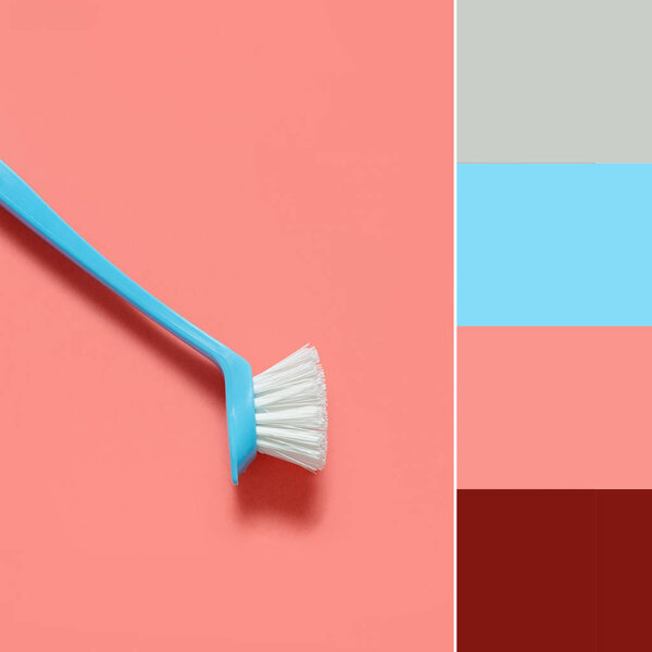 Color matching palette. Pale blue brush for washing dishes lying on living coral background. In the style of pop art. Top view. 