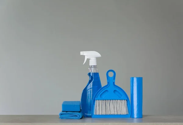 蓝色清洁设置在中性背景 喷雾洗涤剂 垃圾袋 防尘布 勺子和扫帚 复制空间 — 图库照片