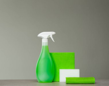 Yeşil püskürtülen ilaç şişe Plastik Sabunluk, sünger ve bez toz gri arka plan üzerinde için temizlik. Temizlik araçları.