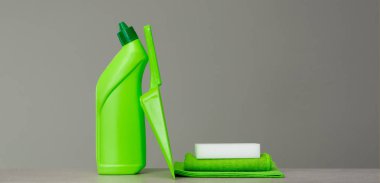 Green detergent bottle for toilet, sponge, scoop and dust cloth on grey background. Cleaning tools. clipart