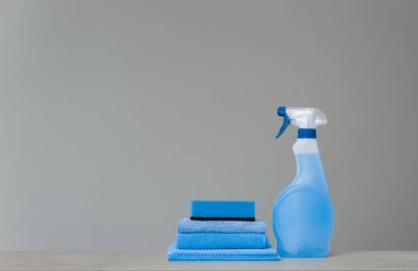 Mavi püskürtülen ilaç şişe Plastik Sabunluk, sünger ve bez toz gri arka plan üzerinde için temizlik. Temizlik araçları. Kopya alanı.