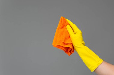 Bir elinde bir lastik eldiven parlak mikrofiber duster tarafsız bir arka plan üzerinde tutar. Parlak bahar, bahar temizliği kavramı.