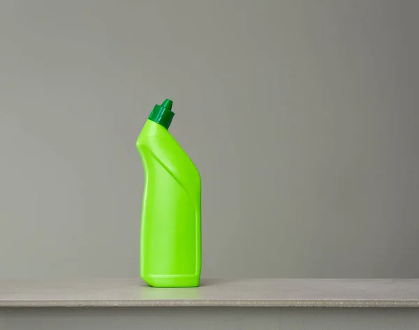 Green bottle of sanitary ware cleaner on grey background.