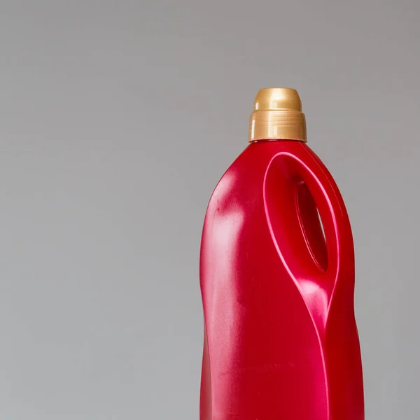 Red bottle of sanitary ware cleaner on grey background.