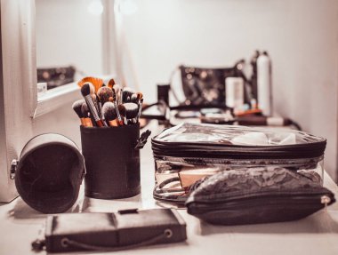 Makyaj sanatçı araçları-makyaj fırçaları ve bir ayna ile masada kozmetik ürünleri.