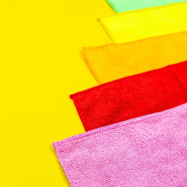 Parlak sarı bir arka plan üzerinde renkli mikrofiber toz örtüsü yalan. Ev işi ekipman kümesi.